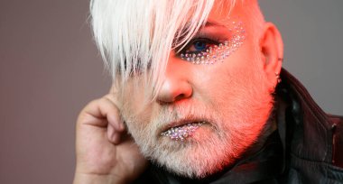 Makyajlı transseksüel adam. Sakallı, yetişkin, göz farı olan bir trans. Transseksüel kimlik. Cinsiyet değişkenliği. Moda transseksüeli. Zarif kirpikleri olan yaşlı trans bir adam. Transseksüel modeli