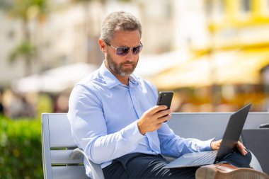 Kendine güveni tam bir iş adamı. Yaz parkında dizüstü bilgisayar ve telefonla bankta oturuyor. Başarı uzaktan yapılan bir iş. Orta yaşlı iş adamı tatilin tadını çıkarıyor. İş adamı bir bankta mola veriyor.