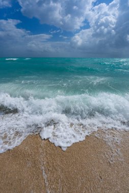Turkuaz deniz dalgası hareketi. Yaz plajı. Sakin deniz. Lüks sahil beldesi. Parlak gökyüzü ve sahilde dalgalar. Güzel köpüklü kıyı şeridi. Deniz arka planı. Mavi okyanus. Kumlu okyanus plajı. Deniz dalgaları