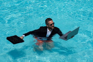 Takım elbiseli çılgın iş adamı havuzda dizüstü bilgisayar kullanıyor. Bilardoda çalışan çılgın bir serbest yazar. Deniz sahilinde dizüstü bilgisayarı olan komik bir iş adamı. Yaz seyahati ve plaj. Yaratıcı çevrimiçi strateji