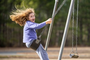 Sarışın çocuk dışarıda sallanıyor. Salıncakta gülen çocuk. Oyun bahçesinde oynayan sevimli çocuk. Heyecanlı çocuk salıncakta sallanıyor. Yaz parkındaki sevimli çocuk. Parkta sallanan oyuncu çocuk. Mutlu çocukluk