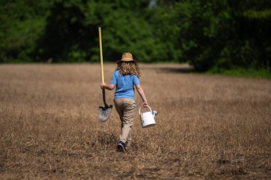Çiftlikte elinde kürek tutan bir çocuk çiftçi. Çocuk çiftçisi çiftçiliğe yardım ediyor. Çiftlikte çalışan çocuk çiftçi. Kırsal alanda çocuk çiftçi. Çocuklarla saha çalışması. Eko çocuk çiftliği