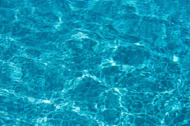 Mavi havuz suyu arka planı. Bulanık şeffaf, durgun su yüzeyi dokusu. Güneş ışığı altında su dalgaları kopyalama alanı ile