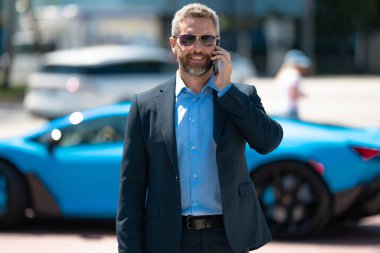 Lüks bir arabanın yanında zengin bir işadamı. Zengin bir iş adamı. Zarif zengin iş adamı. Pahalı arabası olan bir patron. Premium arabada duran zengin bir iş adamı. İş başarısı. Zenginlik kavramı