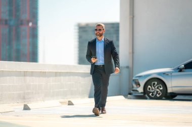 Başarılı bir iş adamı telefonu açık havada tutar. İş adamı dışarıda telefonla konuşuyor. Takım elbiseli olgun iş adamı. Şirket işi. Takım elbiseli zengin iş adamı. Açık hava iş portresi