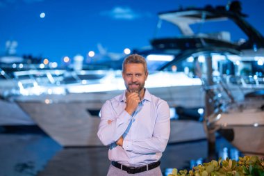 Yatın yanında zengin bir milyoner. Zengin milyoner adam lüks yaşam tarzının tadını çıkarıyor. Özel bir yatta milyoner bir adam. Finansal özgürlük. Milyoner bir işadamıyla pahalı bir yat.