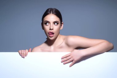 Kadın boş bir tahtayla geliyor. Arkaplanda reklam panosu tutan çekici genç bir kadının portresi. Boş metin, boşluğu kopyala. Boş tabela gösteren bir kadın. Boş tahtanın arkasındaki kız