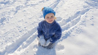 Çocuk karla oynuyor. Kış çocuğu kar taneleriyle oynar. Çocuklar kış tatili. Kış çocukları portresi. Kışın çocukluk anıları. Kışın bir çocuğun portresi. Kar eğlencesi