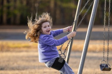 Heyecanlı çocuk eğleniyor. Çocuk bahçesinde mutlu bir çocuk. Havada sallanan kaygısız çocuk. Mutlu çocuklar dışarıda oynuyor. Sarışın çocuk heyecandan titriyor. Dışarıdaki oyuncu çocuk. Komik çocuk suratı