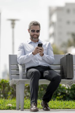 Kendine güveni tam bir iş adamı. Yaz parkında dizüstü bilgisayar ve telefonla bankta oturuyor. Başarı uzaktan yapılan bir iş. Orta yaşlı iş adamı tatilin tadını çıkarıyor. İş adamı bir bankta mola veriyor.