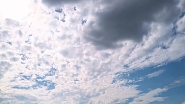 Gökyüzü zaman ayarlı. Hareket eden bulutlar ve güneş. Beyaz kabarık bulutlar mavi gündüz vakti gökyüzünde yavaşça süzülür. Güzel gökyüzü hareket ediyor. Beyaz kümülüs ve sirrus