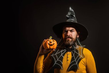 Cadılar Bayramı balkabaklı komik bir model. Cadılar Bayramı şapkalı balkabaklı insan portresi. Şeker mi şaka mı? Cadılar Bayramı şapkalı korkunç hippi. Cadı şapkalı adam balkabağını tutuyor. Mutlu Cadılar Bayramı