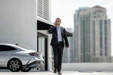 Başarılı bir iş adamı açık havada telefonla konuşuyor. İş adamı dışarıda telefon kullanıyor. Takım elbiseli olgun iş adamı. Şirket işi. Takım elbiseli zengin iş adamı. Açık hava iş portresi