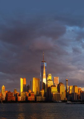 New York şehri. New York şehir manzarası. New York 'taki Lower Manhattan ve One World Trade Center. Manhattan 'ın gökdelenleri New York körfezinin dalgalanan sularının yanında mavi gökyüzüne karşı. New York gökdelenleri