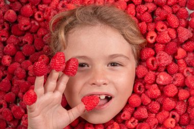 Ahududu yiyen çocuk. Ahududu suratlı çocuk, yakından bak. Ahududulu çocuk yüzü fotoğrafı. Parmaklarda ahududu, yaz tabelası