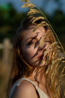 Güzel bir genç kadının yakın plan portresi. Yaz ışığında dışarıda poz veren bir kız. Doğal güzellik kadını. Kadın suratı. Yumuşak tenli güzel bir yüz. Moda kadını.