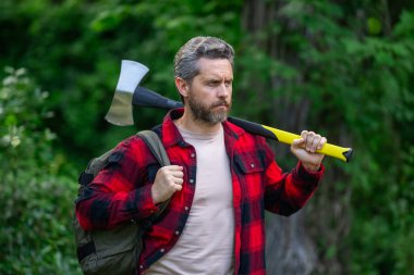 Kendine güvenen oduncu yaz ormanlarında çalışıyor. Baltalı adam. Ormanda ekose gömlekli bir oduncu. Baltalı hippi. Baltalı oduncu. Sakallı oduncu. Baltalı Amerikalı oduncu.