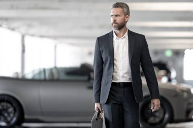 Zengin bir iş adamı pahalı lüks bir arabada. Takım elbiseli zengin bir iş adamı. Şehirdeki başarılı zengin iş adamı. Kendine güvenen bir iş adamı. Başarı işi. İş adamı sokakta yürüyor