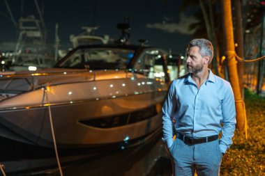 Yatın yanındaki zengin milyarder. Lüks yaşam tarzı olan zengin karizmatik milyarder iş adamı. Özel yatta milyarder bir adam. Finansal özgürlük. Milyarder bir iş adamıyla pahalı bir yat.