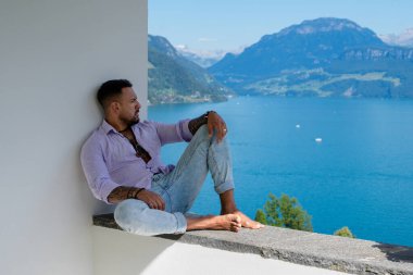 Kaslı bir adam dağ Alpleri manzarasında rahatlar. Alp Gölü 'nde yakışıklı bir turist. Yazın poz veren güçlü, seksi bir adam. Hayalperest, kaygısız bir gezgin. Açık havada insan özgürlüğü