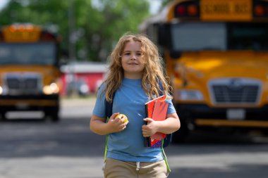 Okula dönelim. Genç öğrenciler için okul başlıyor. Okul otobüsünün yanında sırt çantalı bir çocuk. Çocuk okula gidiyor. Çocuk derse gidiyor. Okul çocuğu.