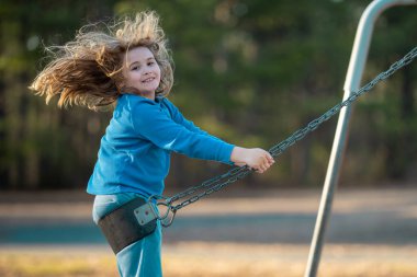 Sarışın çocuk dışarıda sallanıyor. Salıncakta gülen çocuk. Oyun bahçesinde oynayan sevimli çocuk. Heyecanlı çocuk salıncakta sallanıyor. Yaz parkındaki sevimli çocuk. Parkta sallanan oyuncu çocuk. Mutlu çocukluk
