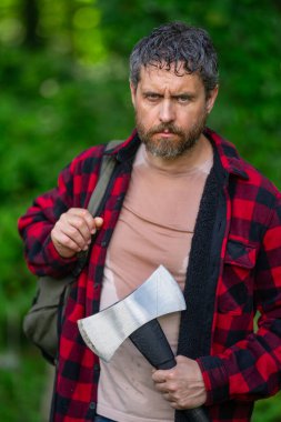 Oduncu vahşi sakallı, kareli gömlekli, baltalı, yeşil doğalı bir adam. Ormanda baltalı bir adam. Zalim oduncu. Elinde balta olan oduncu. Oduncu adam. Balta oduncusu ekipmanı