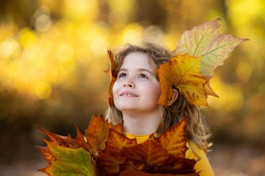 Sonbahar sonbahar parkında çocuk portresi. Küçük çocuk sonbahar yapraklarını, açık hava portresini tutar. Sonbahar parkında sonbahar yapraklı şirin bir çocuk yüzü. Çocuk tutacağı düşen yapraklar. Çocukların açık hava portresi