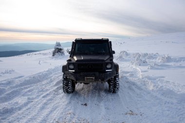 01.02.2021, Karpatlar. Gün batımında kar içinde off-road SUV. 4x4 jipli bir kış seferi. Kış doğasında zorlu bir off-road gezisi. Off-road arabalı dağ yolu. Kar yolunda macera gezisi