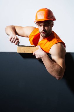 Tuğlalı bir inşaatçı, şantiyede komik satışlar. Kasklı, tuğla işi yapan komik bir inşaatçı. İnşaatçı tuğla bloklarla poz veriyor. Tuğlacı konsepti. Uyanık tamirci. Şapkalı tamirci.