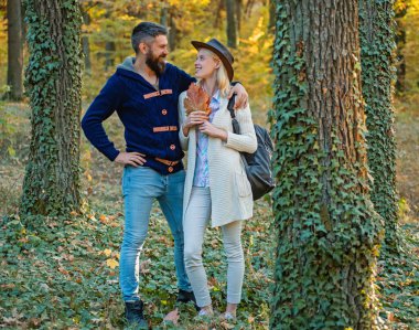 Güzel bir kadın ve yakışıklı bir adam parkta yürüyor ve güzel sonbahar doğasının tadını çıkarıyor. Sonbahar sonbahar parkında bir çift. Sonbahar mevsimi yakınlarındaki erkek ve kadın yaprakları