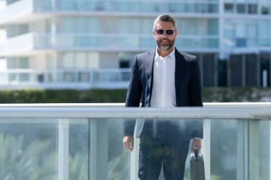 Şehir manzaralı bir balkonda duran bir iş adamı. Başarılı bir iş adamı yazın açık havada eğleniyor. Takım elbiseli bir iş adamı. İş başarısı. Şehir manzarası geçmişi olan bir iş adamı