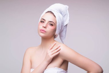 Göz bandı. Göz altlarında kolajen pedleri olan güzel kadın yüzü. Stüdyo çekimlerinde genç bir kadının gözlerinin altına kolajen bantları yapıştırılmış taze ve sağlıklı bir derisi var. Kafasına havlu takıyor ve yüz bakımı yaptırıyor.