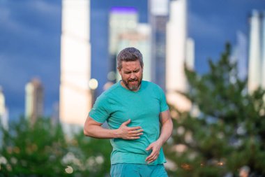 Dışarıda kalp krizi geçiren bir adam. Göğsünü acı içinde tutan bir adam. Parkta kalp krizi geçiren bir adam. Yürürken göğsünde ağrı hisseden bir adam.