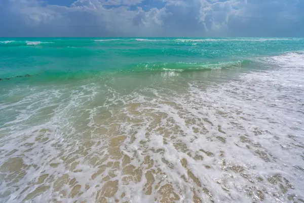 Turkuaz deniz dalgası hareketi. Yaz plajı. Sakin deniz. Lüks sahil beldesi. Parlak gökyüzü ve sahilde dalgalar. Güzel köpüklü kıyı şeridi. Deniz arka planı. Mavi okyanus. Kumsal. Deniz dalgaları