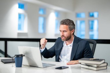 Ofisinde dizüstü bilgisayarı olan bir iş adamı. Modern ofiste çalışan uzaktan kumandalı personel. İş adamı çevrimiçi toplantıda. İnternette çalışan kızgın bir iş adamı. İş yerinde laptop kullanan olgun bir iş adamı