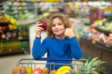 Çocuk bakkaldan alışveriş yapıyor. Süpermarketteki çocuk. Markette alışveriş arabası olan çocuk. Çocuk markette sağlıklı gıda alışverişi yapıyor. Çocuklu bir bakkal. Bakkaldaki organik yiyecekler.