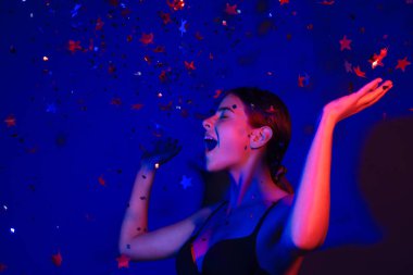 Doğum günün kutlu olsun. Konfeti üfleyen kızın stüdyo portresi. Doğum gününde ya da sevgilisinde konfeti olan güzel kız. Seksi model doğum gününde konfeti üflüyor. Doğum günü esprilerini kutlayan şehvetli kadın.