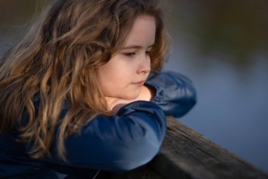 Bir çocuğun gözlerinde huzur ve ilham. Masumiyet ve mucize bir portrede yakalanır. Küçük hayalperest portresi. Açık havada çocukluk anı. Sarışın çocuk dışarıda huzurlu bir anın tadını çıkarıyor.