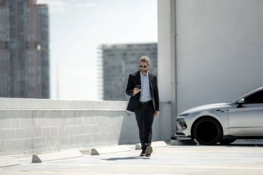 Başarılı bir iş adamı telefonu açık havada tutar. İş adamı dışarıda telefonla konuşuyor. Takım elbiseli olgun iş adamı. Şirket işi. Takım elbiseli zengin iş adamı. Açık hava iş portresi