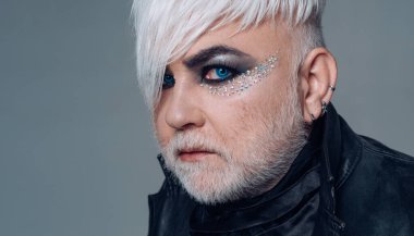 Makyajlı transseksüel adam. Sakallı, yetişkin, göz farı olan bir trans. Transseksüel kimlik. Cinsiyet değişkenliği. Moda transseksüeli. Zarif kirpikleri olan yaşlı trans bir adam. Transseksüel modeli