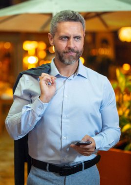 Gece lambasında telefonla konuşan bir iş adamı. İş adamı cep telefonu kullanıyor. Olgun iş adamı internette sohbet ediyor. İş adamı bir arama yapıyor. İş konuşmaları. İş adamı dışarıda telefonla konuşuyor.