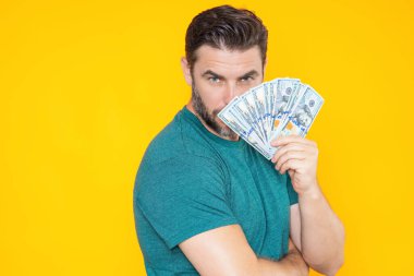 Yakışıklı adam gri stüdyoda izole edilmiş para tutuyor. Dolar banknotları halinde para. Yığınla para, finans, yatırım ve tasarruf