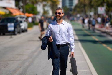 İş adamı işe yürüyerek gider. İspanyol işadamı sokakta güvenle yürüyor. Ofis çalışanı ofise gidiyor. Orta yaşlı iş adamı şehirde yürüyor. Yazlık kıyafetli bir iş adamı.