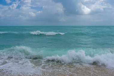 Turkuaz deniz dalgası hareketi. Yaz plajı. Sakin deniz. Deniz kıyısındaki tatil. Parlak gökyüzü ve sahilde dalgalar. Güzel köpüklü kıyı şeridi. Deniz arka planı. Mavi okyanus. Kumlu okyanus plajı. Deniz dalgaları
