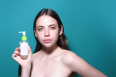 Losyonlu spa tedavisi. Güzellik ürünüyle izole edilmiş bir kız portresi. Su şişesi olan bir kadın model. Kozmetik konsepti. Kadın yüzü ve kozmetik konteynırına yakın çekim