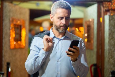 Gece lambasında telefonla konuşan bir iş adamı. İş adamı cep telefonu kullanıyor. Olgun iş adamı internette sohbet ediyor. İş adamı bir arama yapıyor. İş konuşmaları. İş adamı dışarıda telefonla konuşuyor.