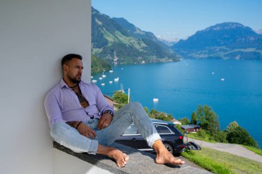 Kaslı bir adam dağ Alpleri manzarasında rahatlar. Alp Gölü 'nde yakışıklı bir turist. Yazın poz veren güçlü, seksi bir adam. Hayalperest, kaygısız bir gezgin. Açık havada insan özgürlüğü