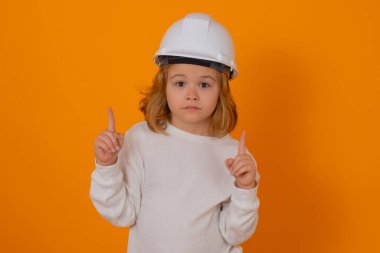 Kasklı, inşaatçı üniformalı bir çocuk. Mühendis kılığında kask takan mutlu çocuk. Becerikli çocuk. Çocuk inşaat işçisi. Çocuk müteahhit. Tamirci kıyafeti giymiş çocuk.