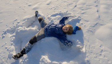 Karlı parkta çocuk oyunu. Çocuk düşen kar taneleriyle oynuyor. Kış eğlencesi Kışın çocuk portresi. Açık havada çocuk kahkahası ve hareket. Donmuş doğadaki duygusal anlar. Çocuklar kış aktiviteleri